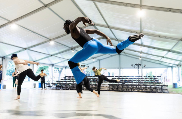 Rhys Carr jumps in the air in foreground as other dancers move in background