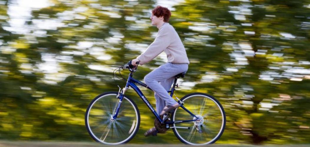 A student rides their bike on a sunny day