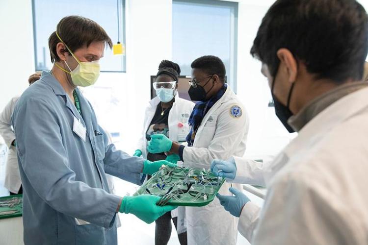 Student handling medical equipment with guidance from others
