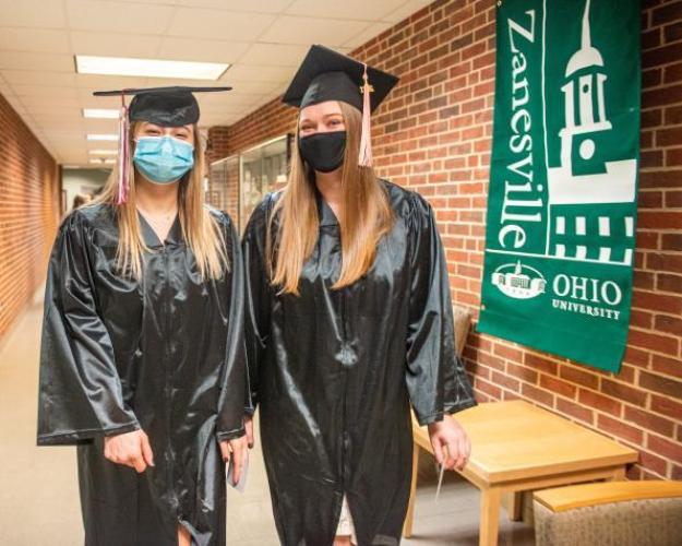Two graduating students dressed in their caps and gowns at the Zanesville graduation commencement