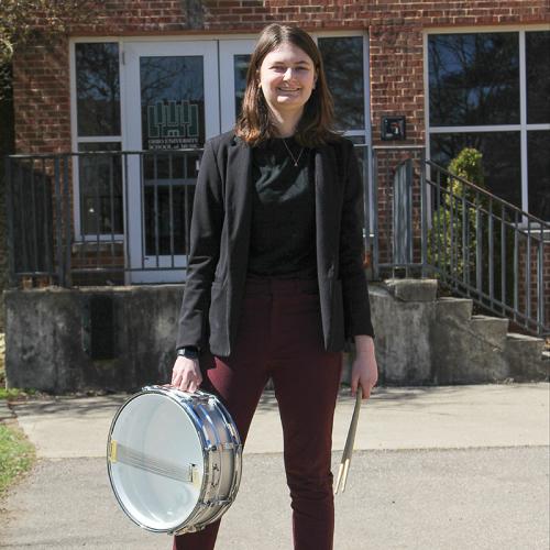 Casey Morarity stands with drum outside Glidden Hall