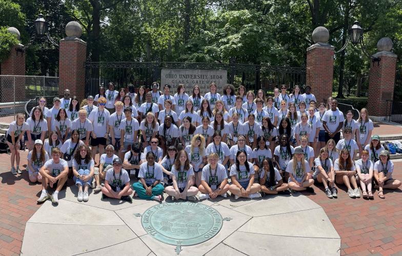 Participants in the High School Journalism Workshop are shown with members of The J Crew in front of the College Gate