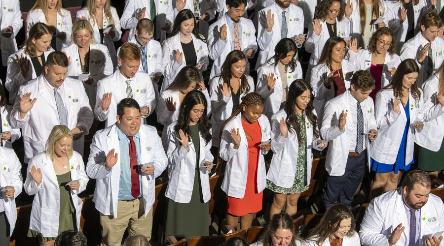 Graduates stand at HCOM white coat ceremony 2023