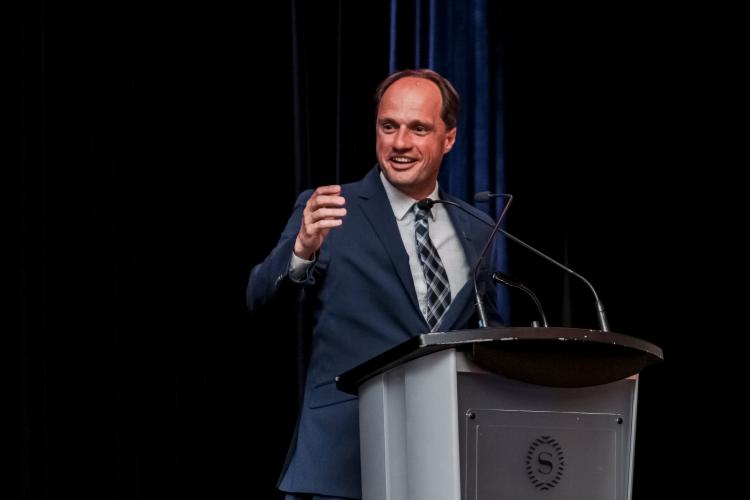 Jim Strode standing at a podium giving award acceptance speech at NASSM annual conference