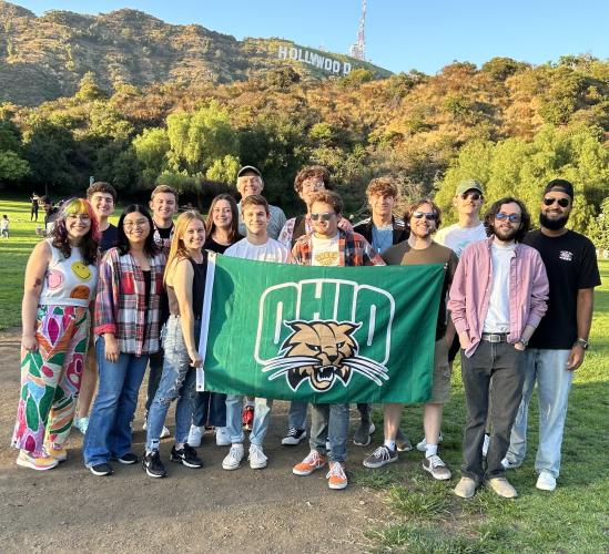 Students in the OHIO-in-LA program pose with an OHIO flag in front of the Hollywood sign in Los Angeles