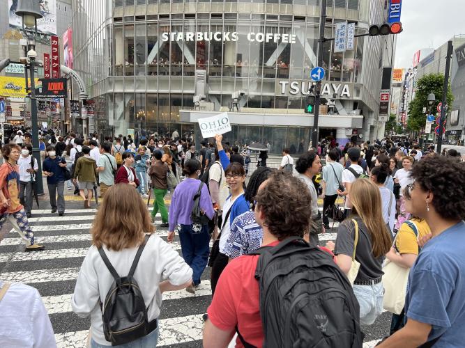 OHIO students follow a guide carrying an Ohio University sign across Tokyo's Shibuya Crossing, the busiest intersection in the world, 