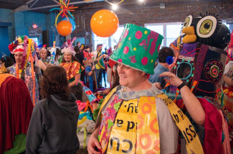 Person in a colorful cloak and tall crafted hat displays artful costume created as part of the annual Honey for the Heart event in Athens Ohio