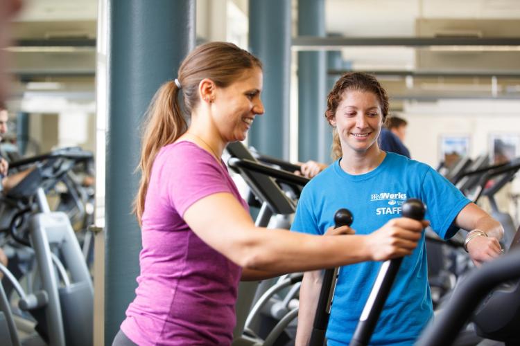 A staff member assist a WellWorks member who is exercising