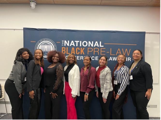 Students pose in front of a National Black Pre-Law Conference banner