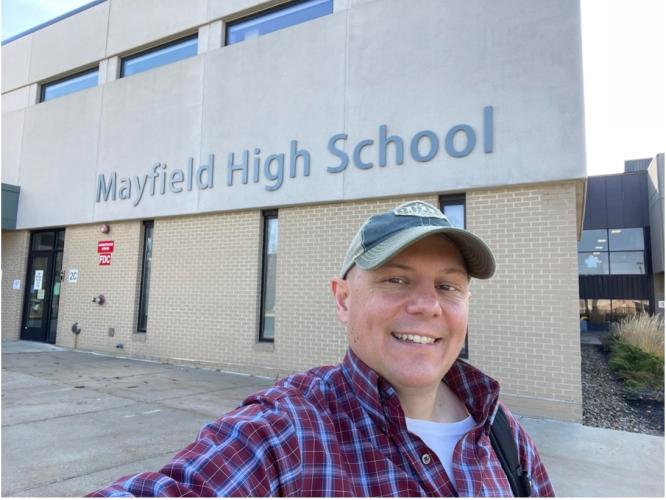 Man in baseball cap takes selfie outside Mayfield High School