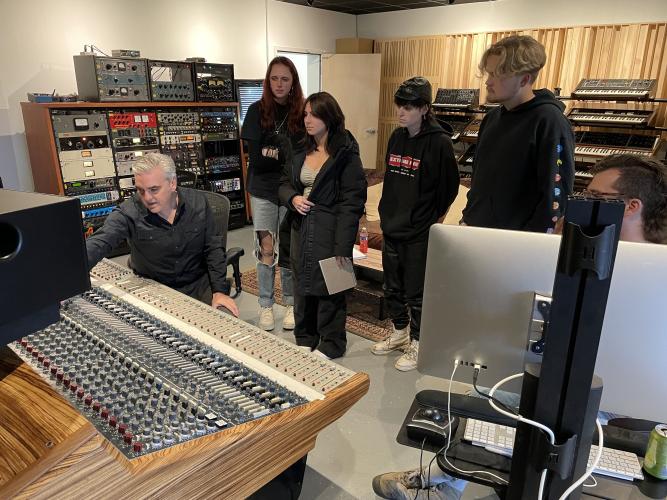 Students observe as producer Jim Eno adjusts a mixing console in Public Hi-Fi Studios.