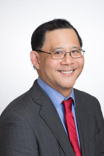 A professional photograph of a man in a suit and red tie