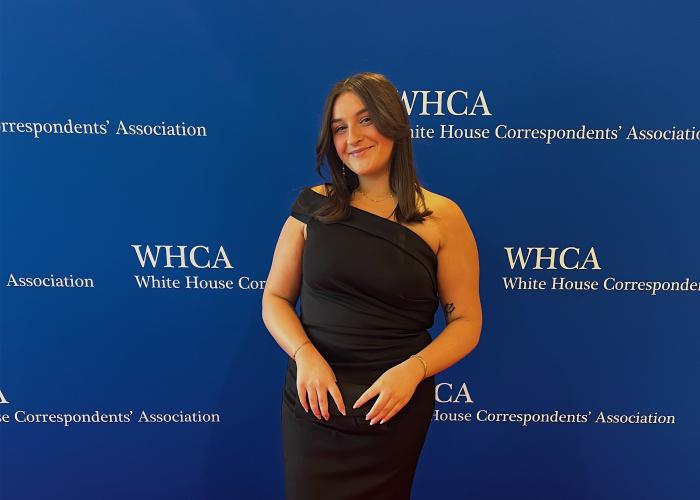 Maddie Harden poses in front of a White House Correspondent's Dinner background