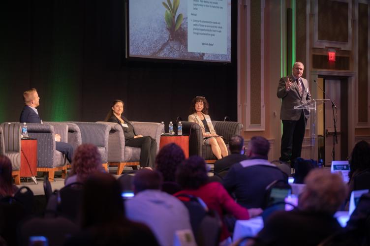 A speaker is shown on stage during the State of the Region Conference