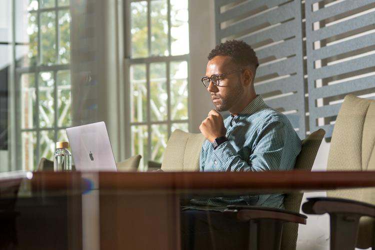 A person in an office deeply focused on their laptop work