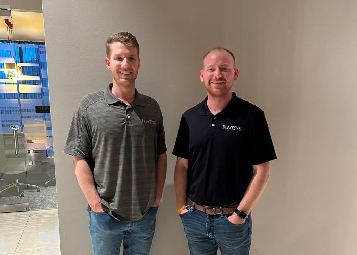 Two men stand side-by-side smiling at the camera