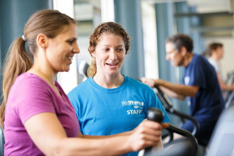 A WellWorks staff member assists an individual who is exercising at WellWorks