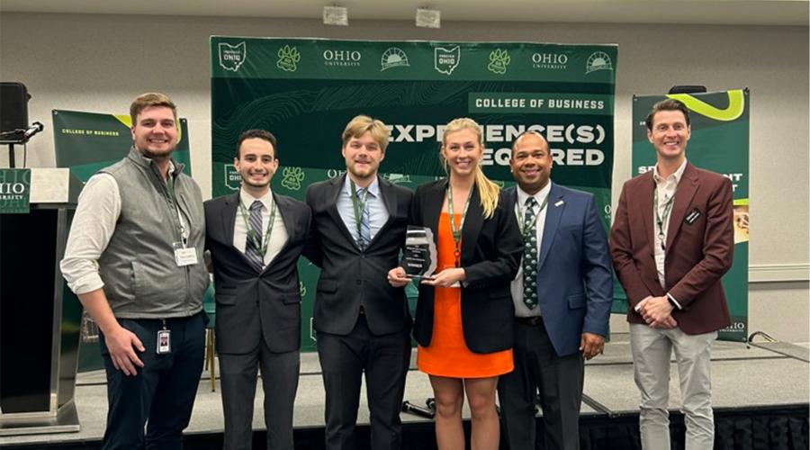 A group of people pose for a picture in a conference room, displaying a trophy