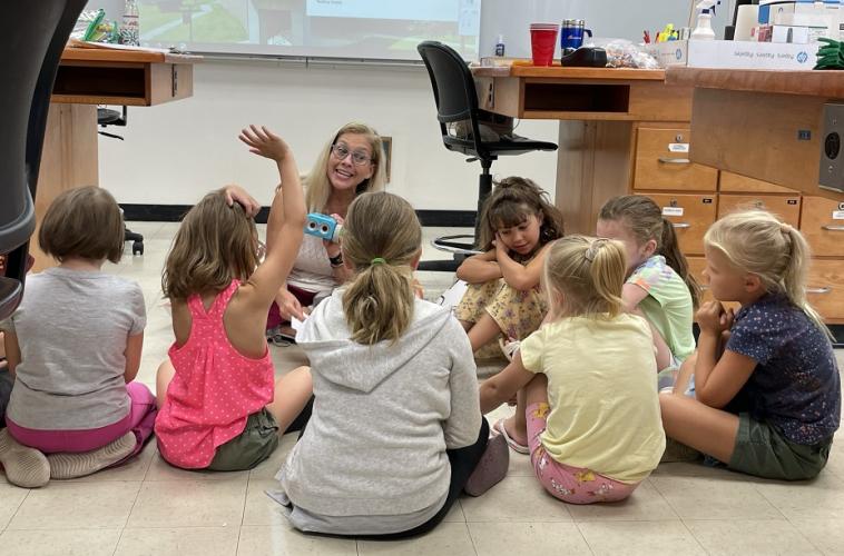 Jenni Domo sits on the floor with a group of kids