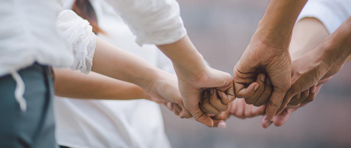 A group of people with hands together in cooperation and teamwork