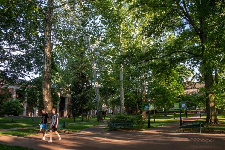 Two students are shown walking on the College Green in the summer