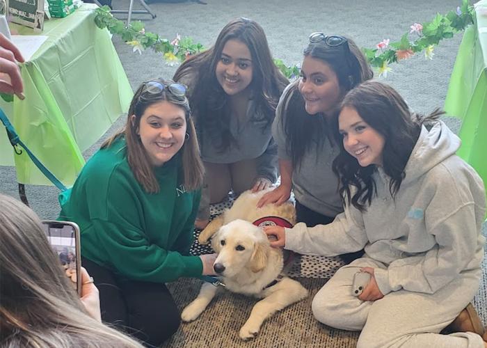 A group of women pose for a picture while petting a puppy