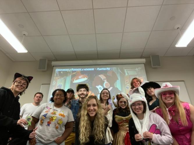 A group of people in costumes pose together, smiling at the camera