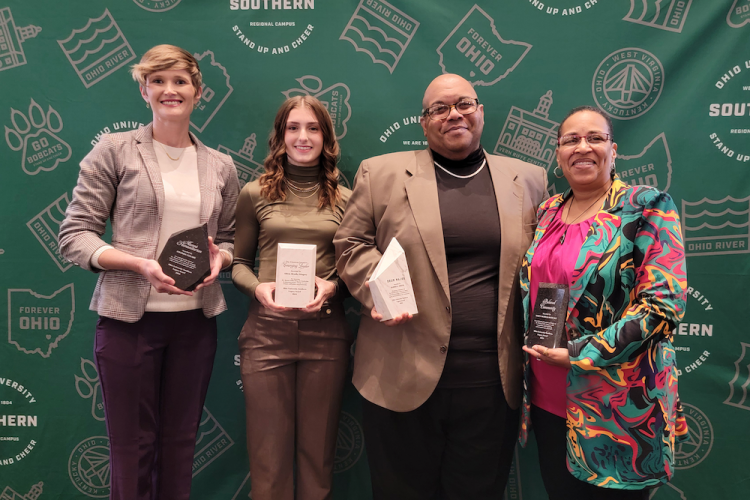 Four people holding awards