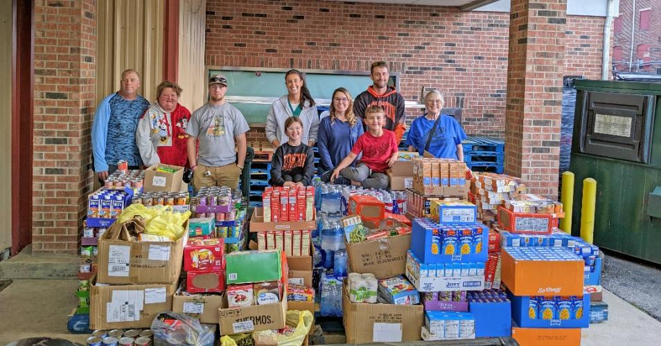 community members stand behind pallet of food donation