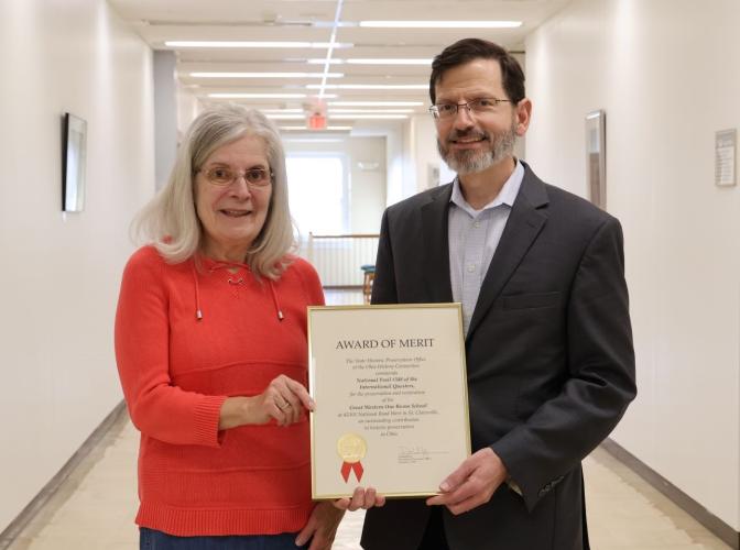 Ann Rattine and David Rohall holding award of merit certificate