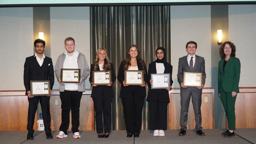 OHIO students Avery Murdock, Kiley Scanlon, Nathan Jennings, Espen Elliot, Manar Al Ghailani, and Mazin Al Jahwari hold their winners certificates while they pose for a photo with Kim Jordan.