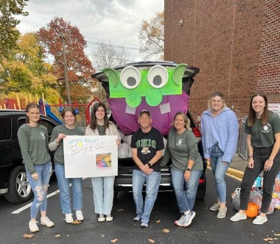 Members of the Student Social Work Association stand next to car that is decorated for Trunk or Treat