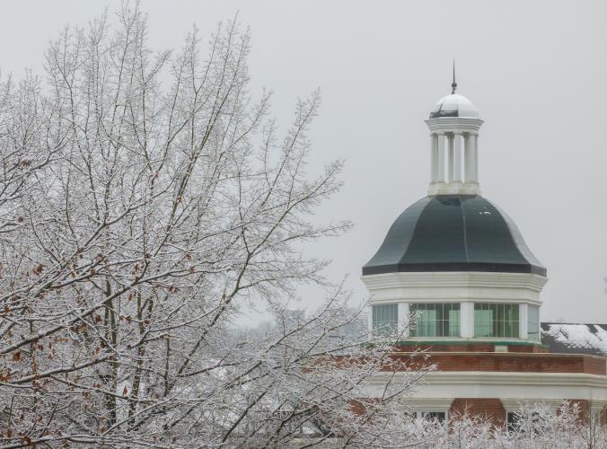 An OHIO building is shown next to a tree covered in ice and snow on a winter's day at Ohio University
