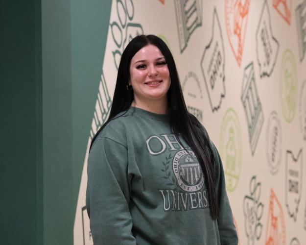 Female student with long black hair wearing a green sweatshirt 