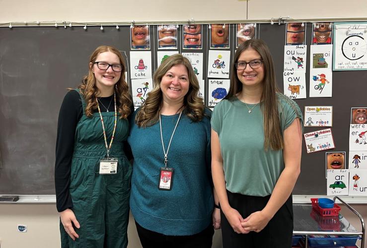 3 female teachers posed in front of blackboard in classroom