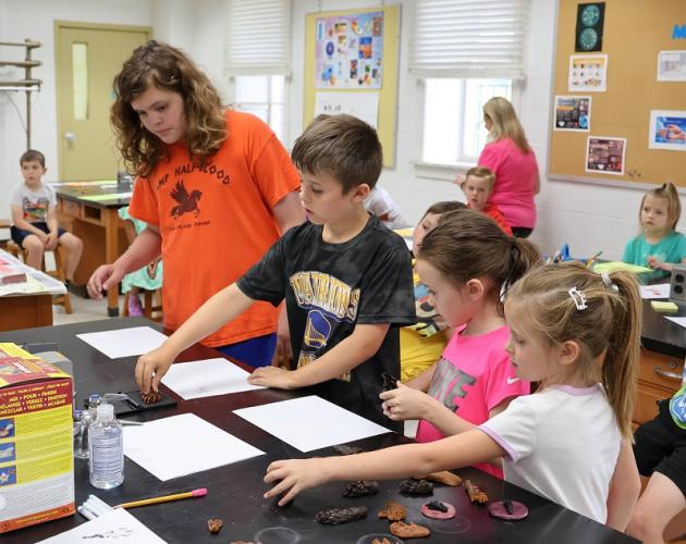 students in a Kids in College STEM class make animal footprints with stamps