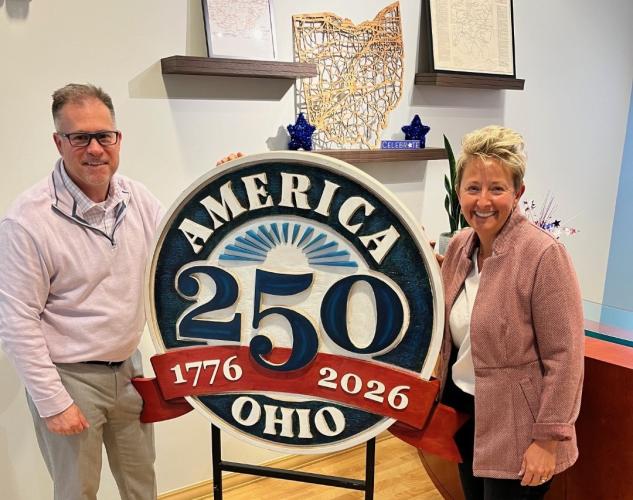 Tom Kleismit and Amista Lipot are shown with an America 250th anniversary sign
