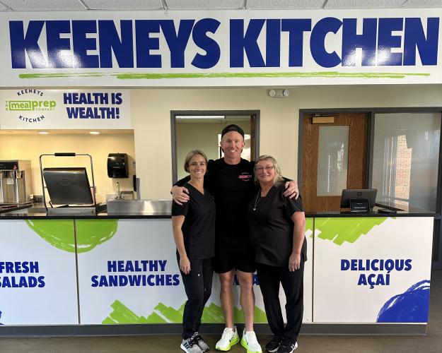 Three people dressed in black below sign reading Keeneys Kitchen