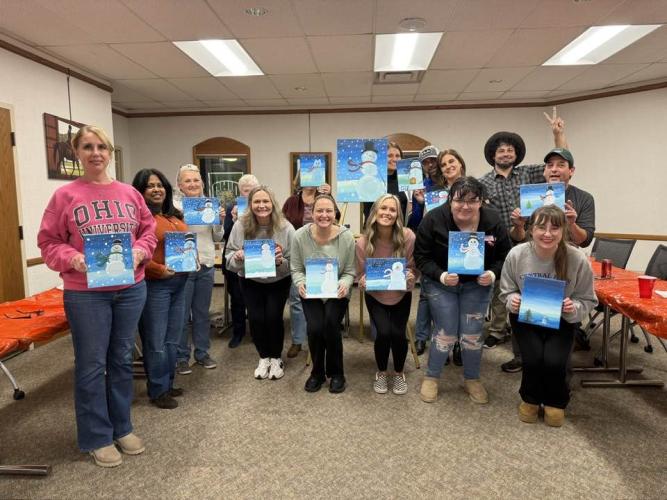Group of people holding up paintings
