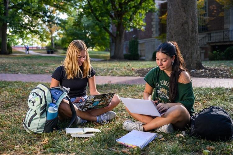 OHIO students work on projects on their laptop computers while sitting on the College Green on a warm day