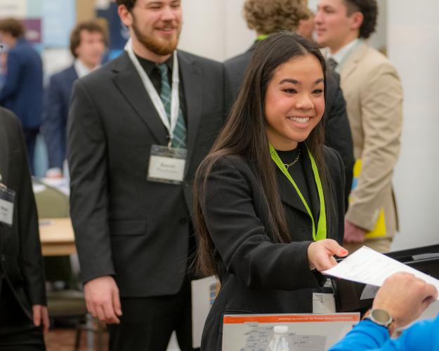 An OHIO student hands a resume to a company representative at a Career Fair at OHIO