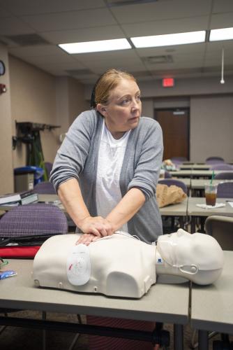 woman performs cpr on dummy