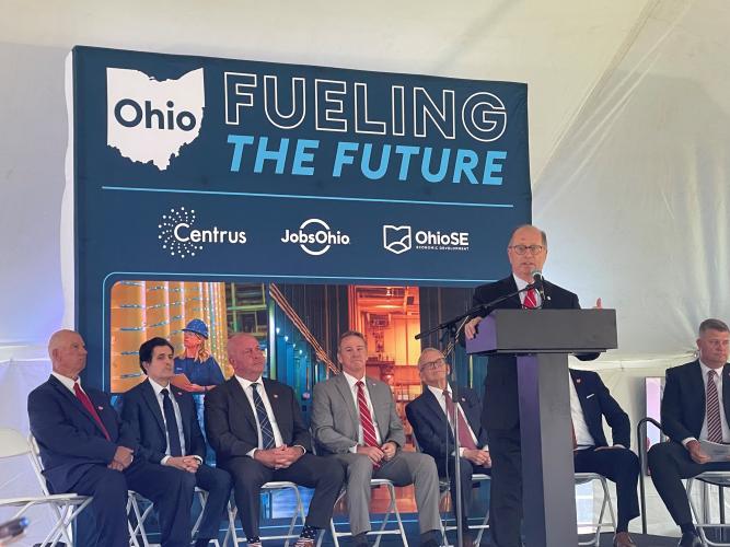 A speaker stands at a podium in front of local and state leaders and in front of a sign that says Ohio - Fueling The Future - Centrus, JobsOhio and OhioSE Economic Development