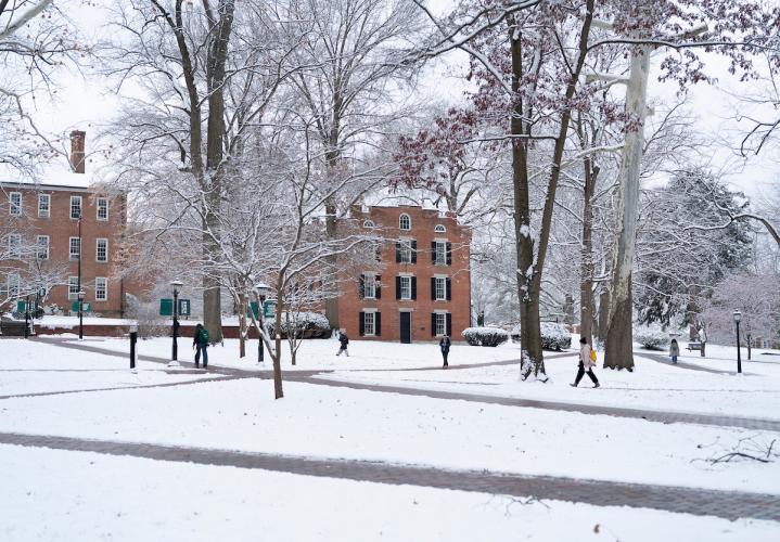 Individuals walk across the snowy College Green at Ohio University