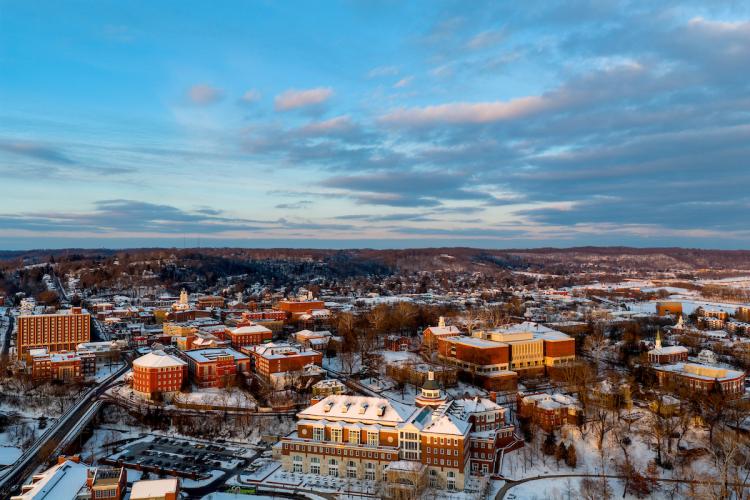 A drone image of Ohio University's Athens Campus, including Baker Center and Alden Library, with the city of Athens in the background and clouds in the sky