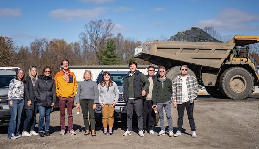 Voinovich Research Scholars and OHIO administrators are shown in front of a large dump truck at a work site