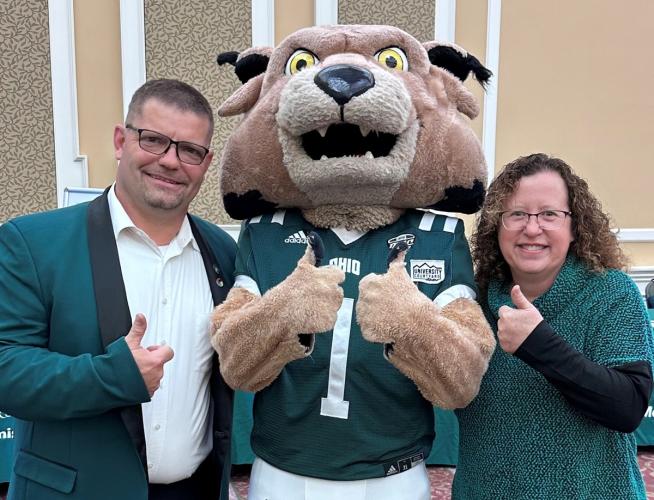 Tracy Watson and Corey Boby stand with the Rufus mascot while inside the Baker University Center Ballroom