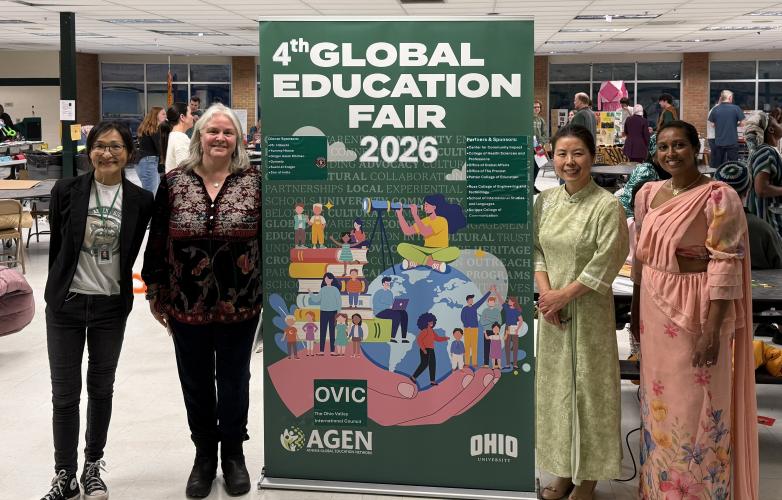 Four OHIO representatives stand in front of the Global Education Fair banner at one of the events