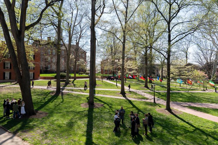 Students walk on the College Green, while international flags are also placed the College Greenon a spring day