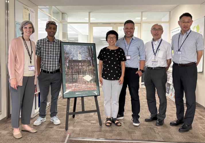 OHIO and Chubu University representatives stand together next to artwork that features OHIO's Cutler Hall